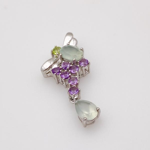 Dije de plata con gemas naturales verdes y moradas sobre fondo blanco - Rocas & Cristales