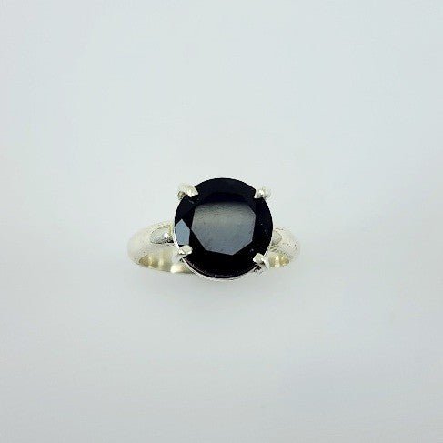 Anillo de Ónix Circular en Plata 950 de diseño minimalista con gema negra facetada sobre fondo neutro. - Anillos