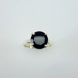 Anillo de Ónix Circular en Plata 950 de diseño minimalista con gema negra facetada sobre fondo neutro. - Anillos