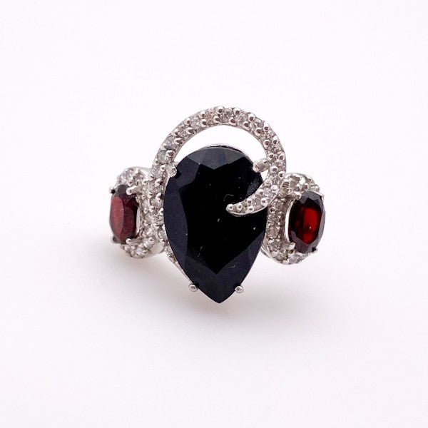 Anillo de Ónix con Granates en Plata 925 con engaste de grifas y cubic zirconia sobre fondo neutro. - Anillos
