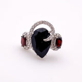 Anillo de Ónix con Granates en Plata 925 con engaste de grifas y cubic zirconia sobre fondo neutro. - Anillos