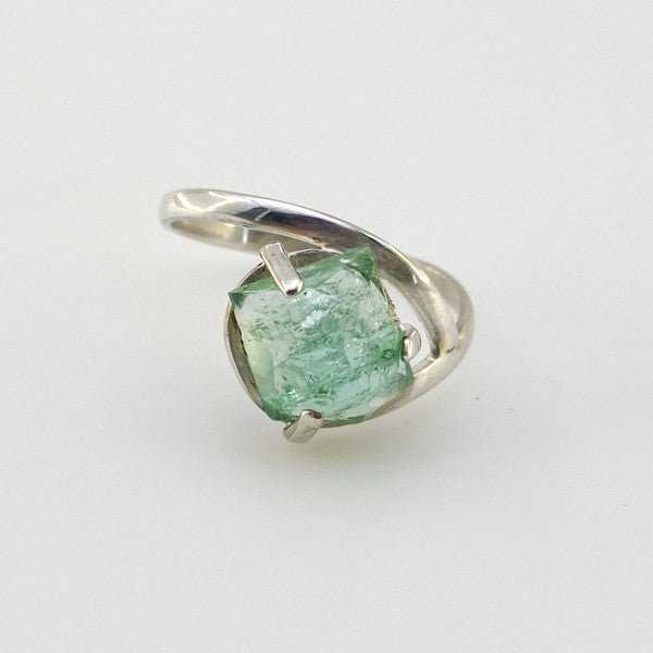 Anillo de Turmalina Verde en Plata 925 con facetado irregular y engaste de grifas rústico sobre fondo neutro - Anillos