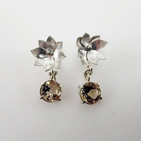 Aros de Topacio Imperial en Plata 950 con diseño floral, corte circular y movimiento sobre fondo neutro.- Aros