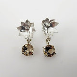 Aros de Topacio Imperial en Plata 950 con diseño floral, corte circular y movimiento sobre fondo neutro.- Aros