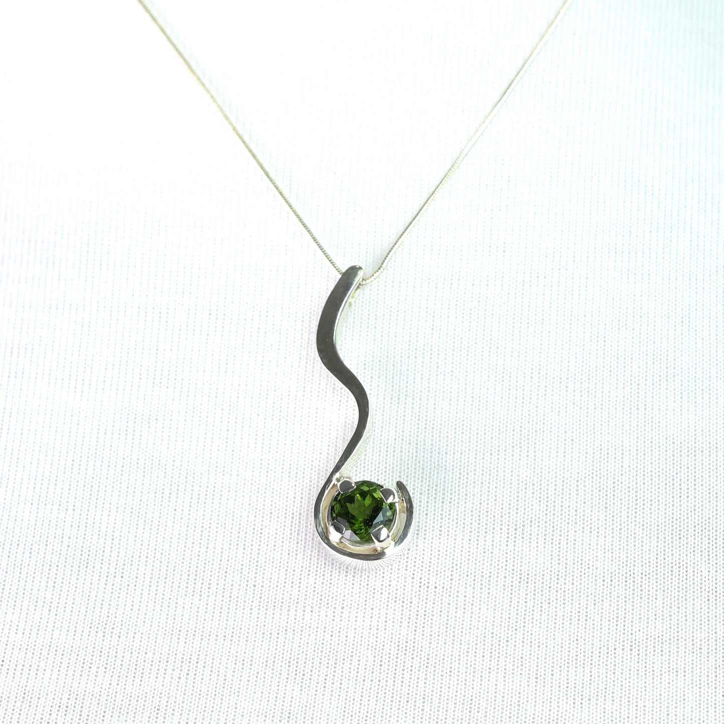 Dije de Moldavita Circular en Plata 950 con piedra natural facetada y cadena cola de rata sobre fondo neutro - Dijes