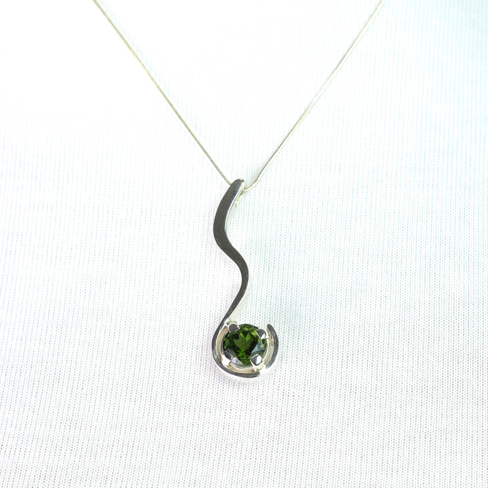 Dije de Moldavita Circular en Plata 950 con piedra natural facetada y cadena cola de rata sobre fondo neutro - Dijes