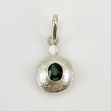 Dije de Turmalina Verde en Plata 950 con engaste cerrado y texturado sobre fondo neutro.- Dijes
