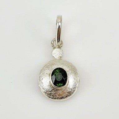 Dije de Turmalina Verde en Plata 950 con engaste cerrado y texturado sobre fondo neutro.- Dijes