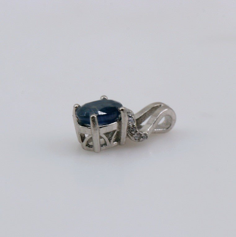Dije de Zafiro en Plata 925 vista frontal detallando la gema oval azul y el brillo de las cubic zirconias. - Dijes