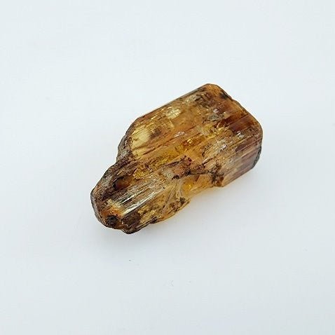 Topacio Imperial en bruto de Brasil con tonalidad marrón caramelo y cristalización rectangular. - Minerales de colección